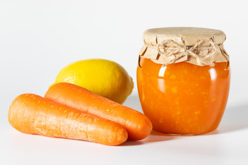 Juicy homemade carrot jam in glass jars on a white background.