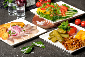 Assorted pickled and fresh vegetables - pickled herring, chopped chives with potato, peppers, cucumbers, tomatoes, capers, salt and herbs. Set of vegetables snacks for alcohol vodka. Russian