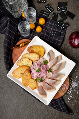White plate of pieces of pickled herring, chopped chives with fried potato, onion, tomato and cold vodka. Russian traditional cuisine. Close up.