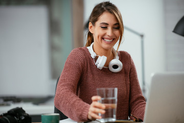 Young businesswoman drinking water in office - Powered by Adobe
