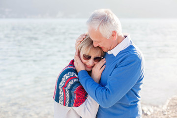 Fototapeta na wymiar Senior couple falling in love at sea beach outdoor. Happy man and woman hugging and enjoying retirement and traveling. Concept of wellbeing, care, happiness, male and female health. Lifestyle moments.