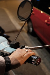 Young girl holds a handlebar of an retro light blue scooter with ring on hand in winter. Close up