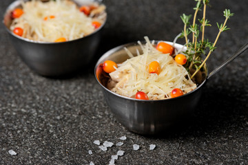 Festive french julienne with sea buckthorn in a bowl on black stone background. Rustic style. Close up, selective focus.