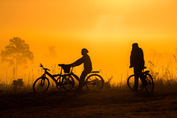 Silhouette of peoples Cyclist look at view fog in the morning