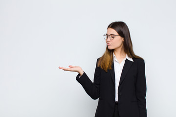 young businesswoman feeling happy and smiling casually, looking to an object or concept held on the...