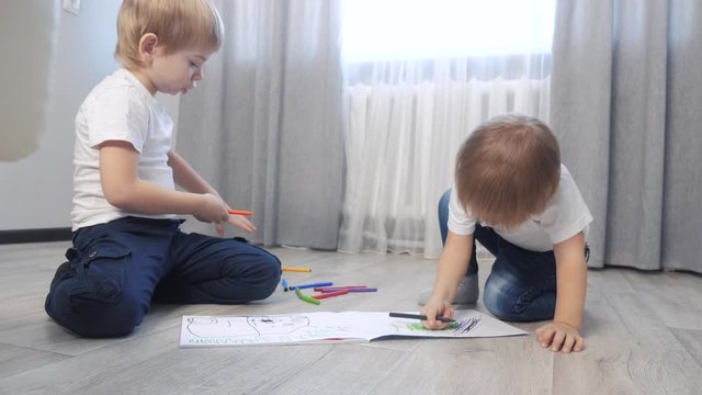 children draw with felt-tip pens in an album. little boy and girl concept childhood brother lifestyle and sister play paint on the floor with colored markers