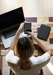 Woman's hands use a smartphone with a laptop. Study and work online, freelance. Self employed or...