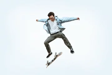 Selbstklebende Fototapeten Caucasian young skateboarder riding isolated on a white studio background. Man in casual clothing training, jumping, practicing in motion. Concept of hobby, healthy lifestyle, youth, action, movement. © master1305