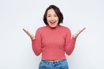 young pretty woman feeling happy, excited, surprised or shocked, smiling and astonished at...