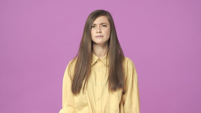 Slow-motion attractive stylish young 20s woman cringe from aversion, squinting, wrinkle nose, grimacing as if looking at something disgusting, very ugly and unpleasant, dislike it, purple background