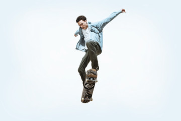 Caucasian young skateboarder riding isolated on a white studio background. Man in casual clothing training, jumping, practicing in motion. Concept of hobby, healthy lifestyle, youth, action, movement. © master1305