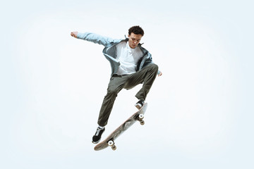 Caucasian young skateboarder riding isolated on a white studio background. Man in casual clothing...