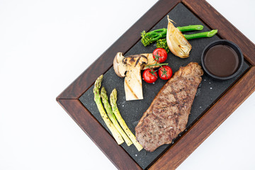 Grilled beef steak ribeye medium rare on wooden cutting board on white stone table. Top view with copy space.