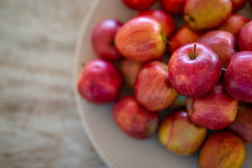 Apples in bowl on bright wooden background, top view