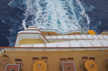 Relaxing on outdoor promenade with sun umbrellas and deck chairs with ocean views on luxury cruise...