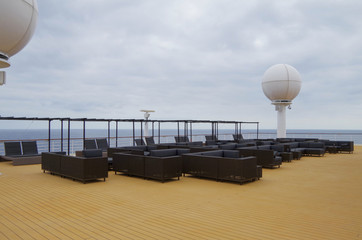 Relaxing on outdoor promenade with sun umbrellas and deck chairs with ocean views on luxury cruise...