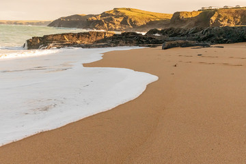 Foam from the receding tide on a deserted Cornish beach