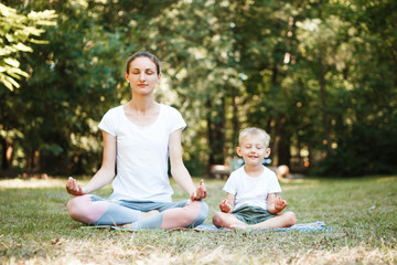 Mom and son do yoga in a summer park. Healthy lifestyle.