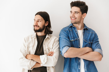 Photo of young happy guys with hands crossed smiling and looking aside
