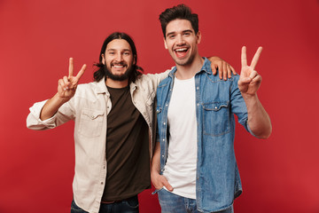 Photo of young happy guys smiling and gesturing peace sign