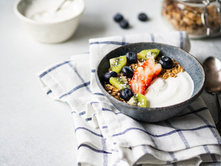 Delicious healthy breakfast - granola with yogurt and berries, yogurt in bowl and granola in glass jar on the table. Copy space.