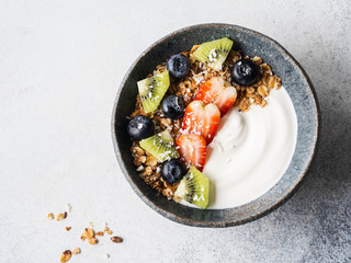 Delicious breakfast - granola in bowl with yogurt, fruit and berries on the table. Top view