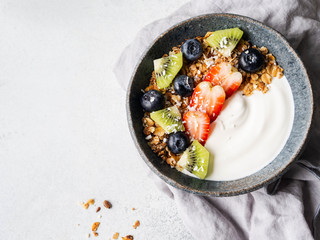 Delicious breakfast - granola in bowl with yogurt, fruit and berries on the table. Top view