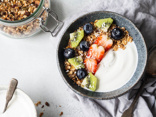 Delicious breakfast - granola in bowl with yogurt, fruit and berries on the table. Top view