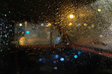Rain drops on window with road light bokeh, City life in night in rainy season abstract...