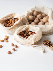 Reusable eco-friendly fabric bags for storage or shopping with various nuts on a white background. Copy space