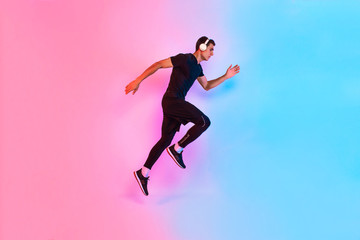 Fototapeta na wymiar Sports man jumps. Dynamic movement. Side view, against a background of red and blue neon light