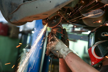 cutting metal part with sparks in car service station close up. sparks fly from a sawing angle grinder © Petr Smagin