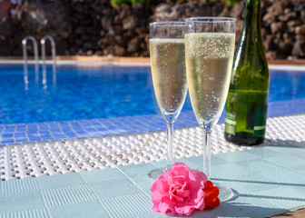 Pool party with two glasses with  bubbles white champagne or cava wine, romantic event or all inclusive holidays