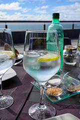 Drinking cold mineral water with bubbles, served in wine glass with ice cubes and lemon