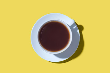 A cup of black coffee or tea on a yellow background. Minimal concept. Flat lay, top view.