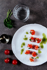 Three stuffed tomatoes on a white plate on grey background