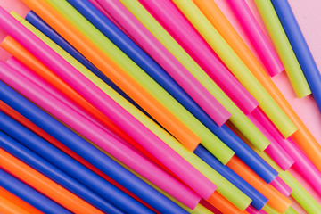 colored tubules for juice and cocktails on pink background. Colorful drink straws. straw, plastic free, reusable plastic drinking background, plastic free. Plastic pollution concept.