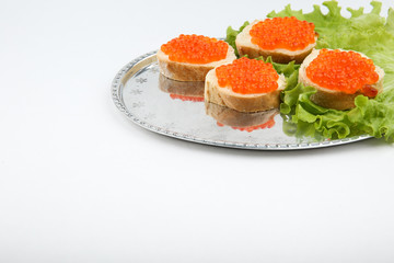 sandwiches with red caviar and lettuce on a silver tray on white background with copy space.