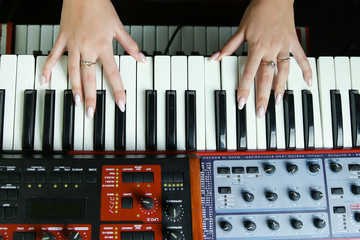 hands of a woman play a synthesizer close up top view