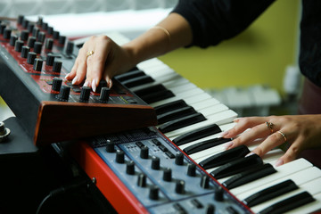 hands of a woman play a synthesizer close up - obrazy, fototapety, plakaty