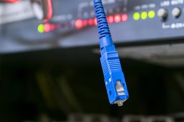 The tip of the optical cable is on a technological background. Fiber optic patch cord is close up.  Concept of high speed internet communication technology. Selective focus