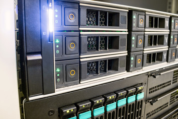 The database server is in the rack of the data center. Modern computer equipment is installed in the server room. Many hard drives are in a powerful router on the hosting site.