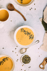 Three bowls with pumkin soup on a white table arranged for lunch