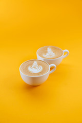 two cups of Latte coffee on yellow background. Monday coffee latte.