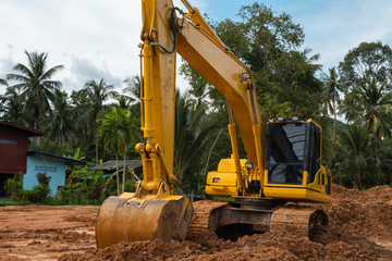 Yellow excavator on a construction site against blue sky. Heavy industry. Close up details of...
