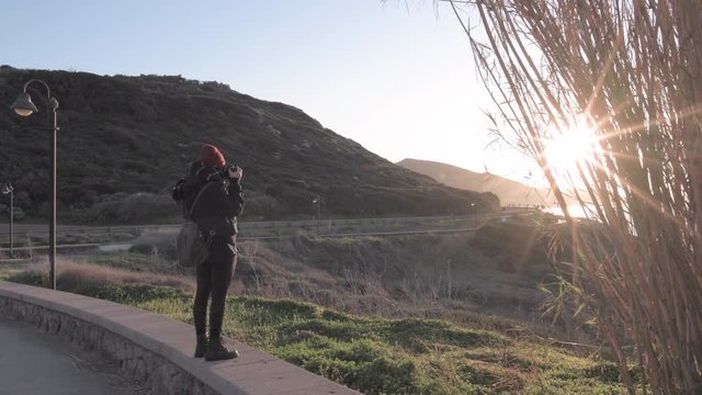 Young woman photographing landcape at sunset