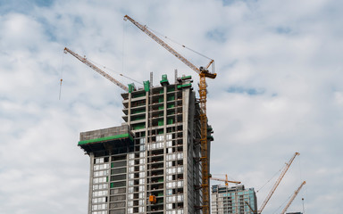 Construction site of building a high-rise building with a cranes against blue sky.