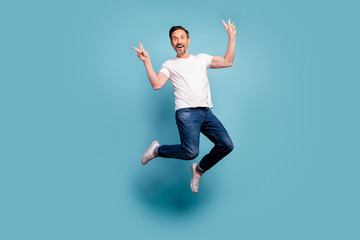 Fototapeta na wymiar Full length body size view of nice attractive cheerful cheery funky comic guy jumping showing v-sign having fun isolated on bright vivid shine vibrant teal green blue turquoise color background