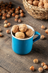 Walnuts in a blue pot with hazelnuts in the background