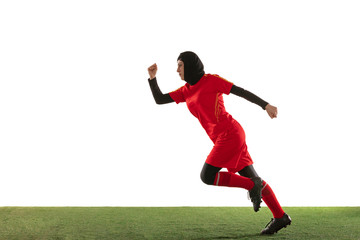 Speed. Arabian female soccer or football player on white studio background. Young woman running for the goal, catched in motion, action. Concept of sport, hobby, healthy lifestyle. Copyspace.